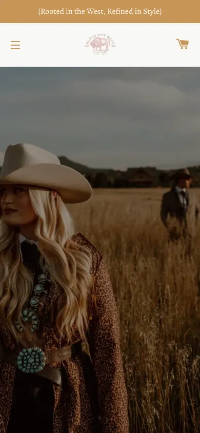 Blush Out West homepage on a phone showing a menu icon, a small bison logo and a cart icon above a full-screen photo of a woman in a leopard jacket and cowboy hat in a wheat field